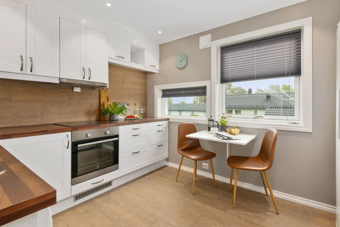 Modern kitchen with white cabinets, wooden countertops, and a cozy dining nook.