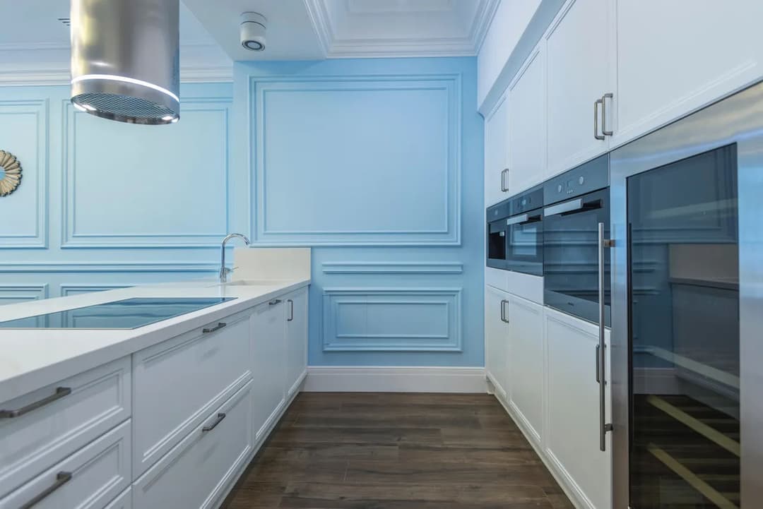 Modern kitchen design with blue accents, sleek white cabinets, and stainless steel appliances.