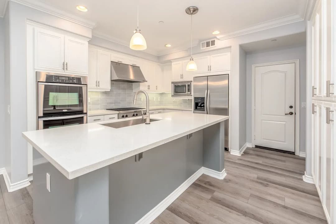 Modern kitchen with white cabinetry, stainless steel appliances, and a spacious island.