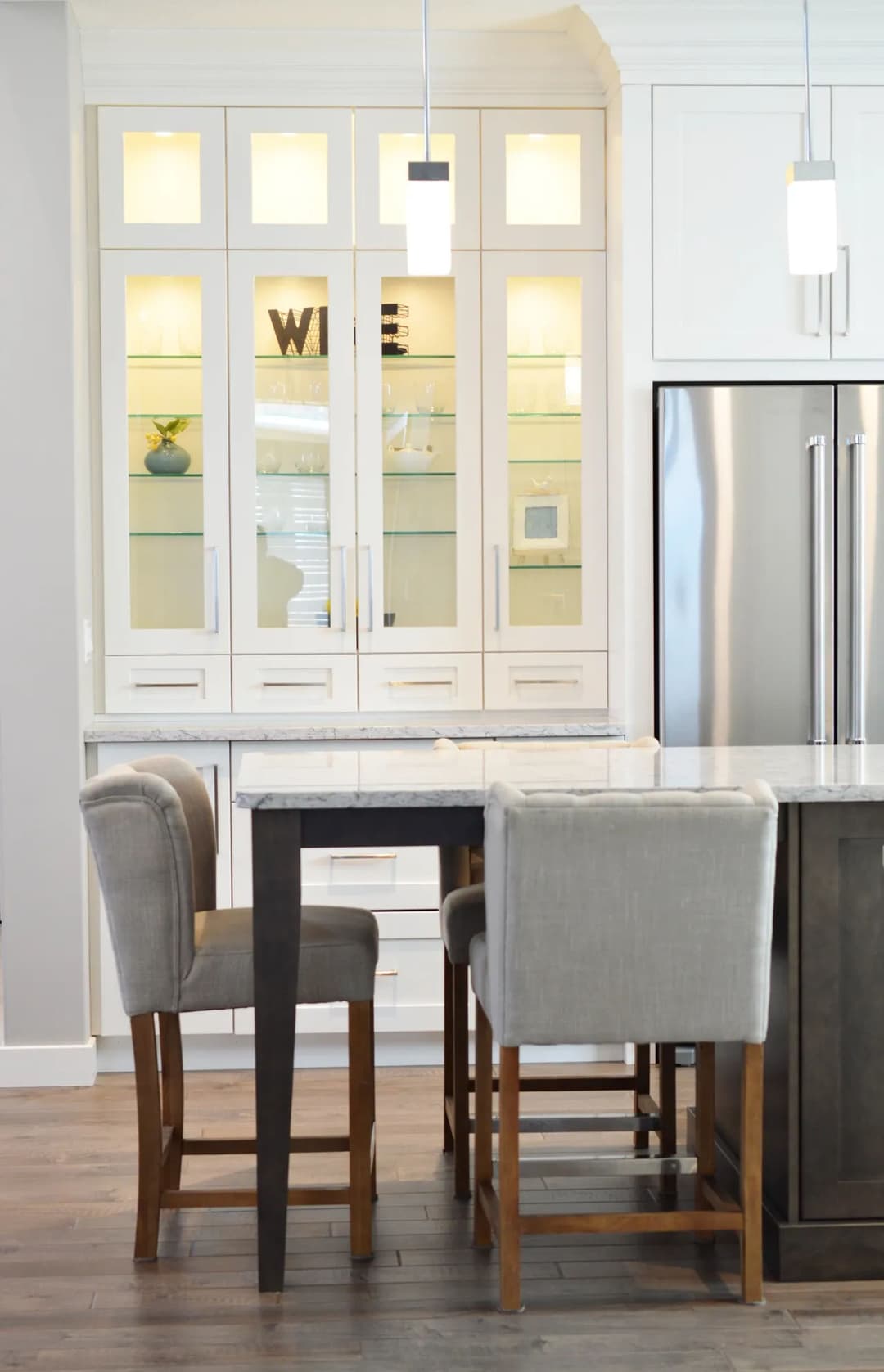 Modern kitchen with glass-front cabinets, marble countertop, and stylish high chairs.