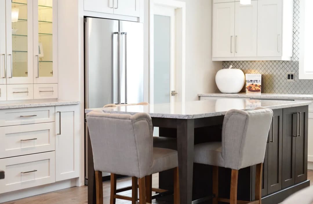 Modern kitchen with stainless steel appliances, white cabinets, and a large island seating area.