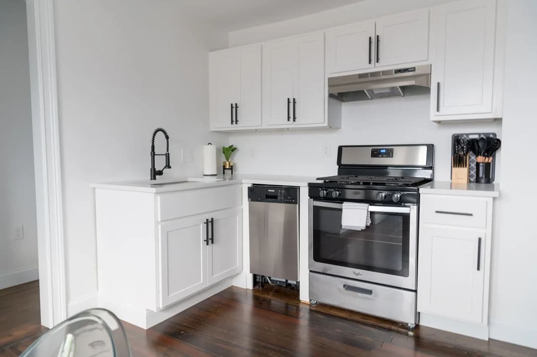 Modern kitchen with stainless steel appliances, white cabinets, and hardwood flooring.