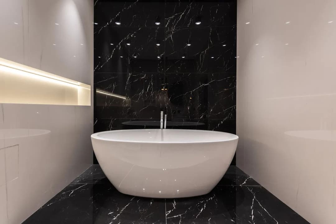 Modern freestanding bathtub in sleek black and white marble bathroom design.