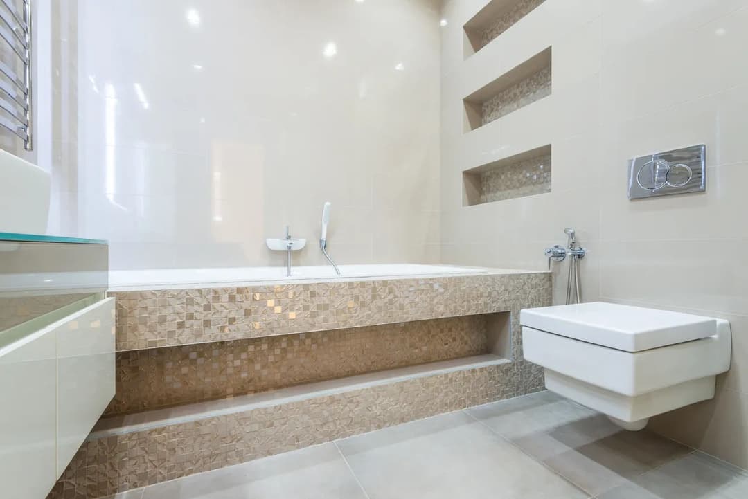 Modern bathroom featuring a sleek bathtub, wall-mounted toilet, and elegant tile design.