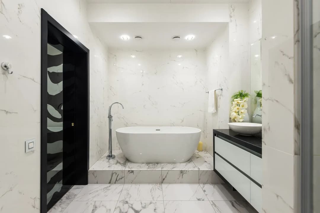 Modern bathroom with a freestanding tub, marble walls, and elegant fixtures.