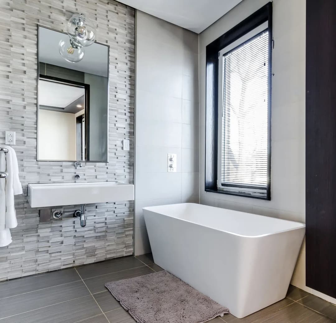 Modern bathroom featuring a freestanding tub, sleek sink, and decorative tile accents.
