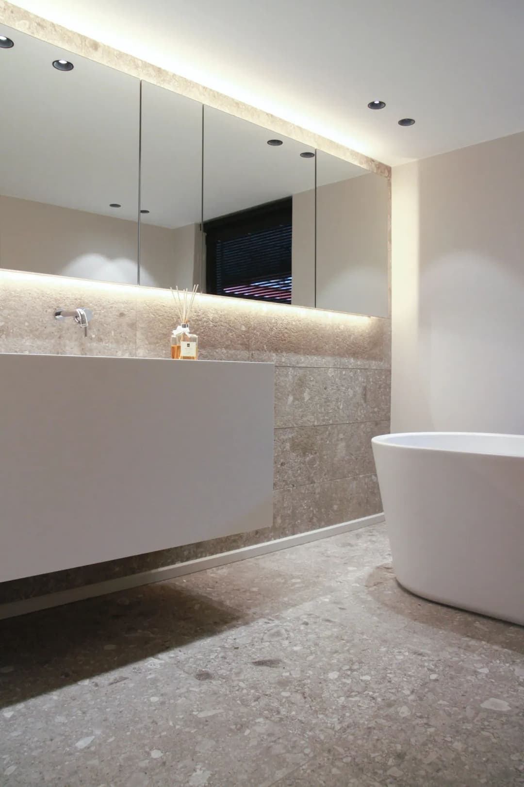 Modern bathroom with minimalist design, featuring a sleek tub and elegant stone accents.