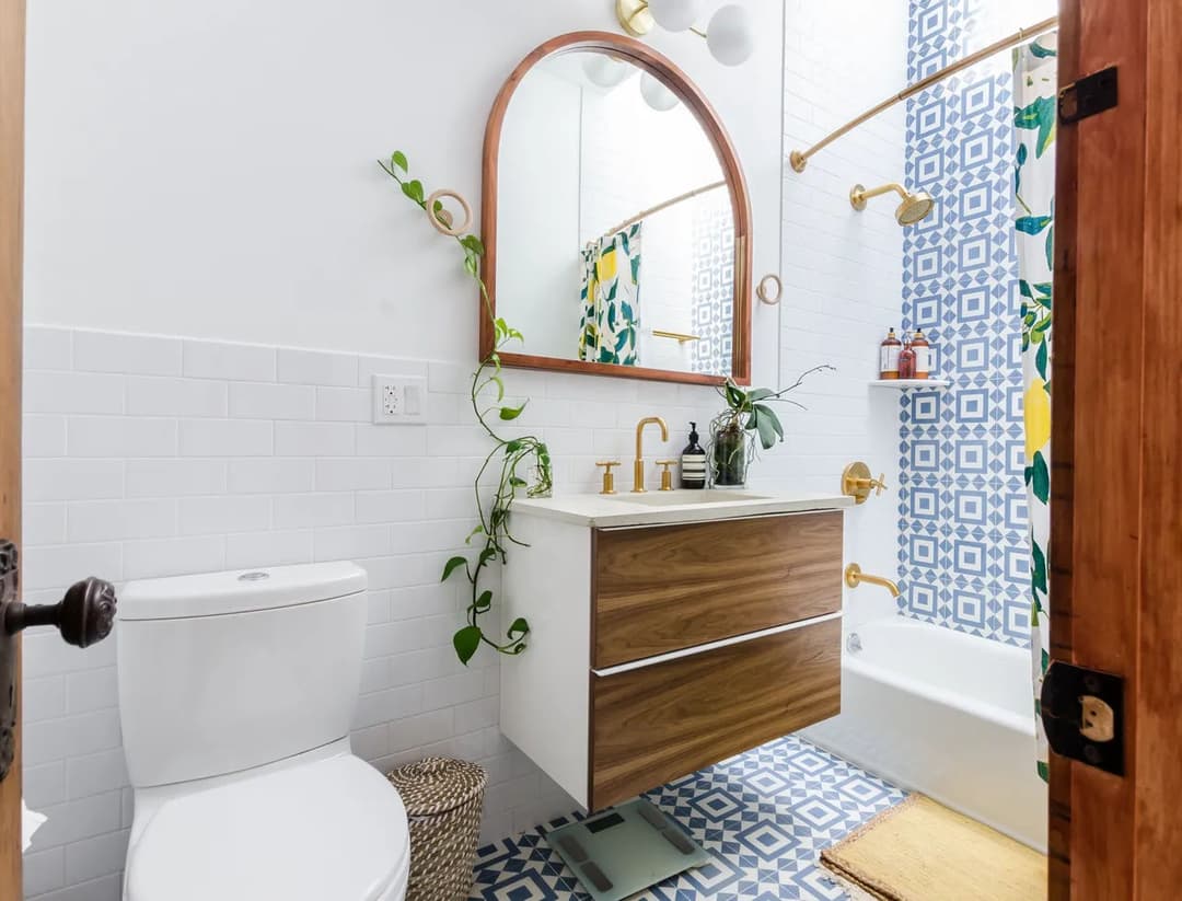 Modern bathroom featuring blue patterned tiles, sleek vanity, and greenery accents.
