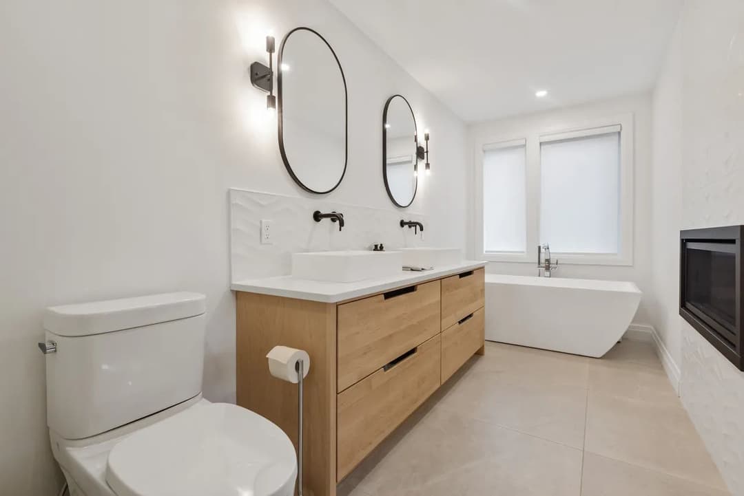 Modern bathroom with dual mirrors, stylish vanity, freestanding tub, and elegant fixtures.