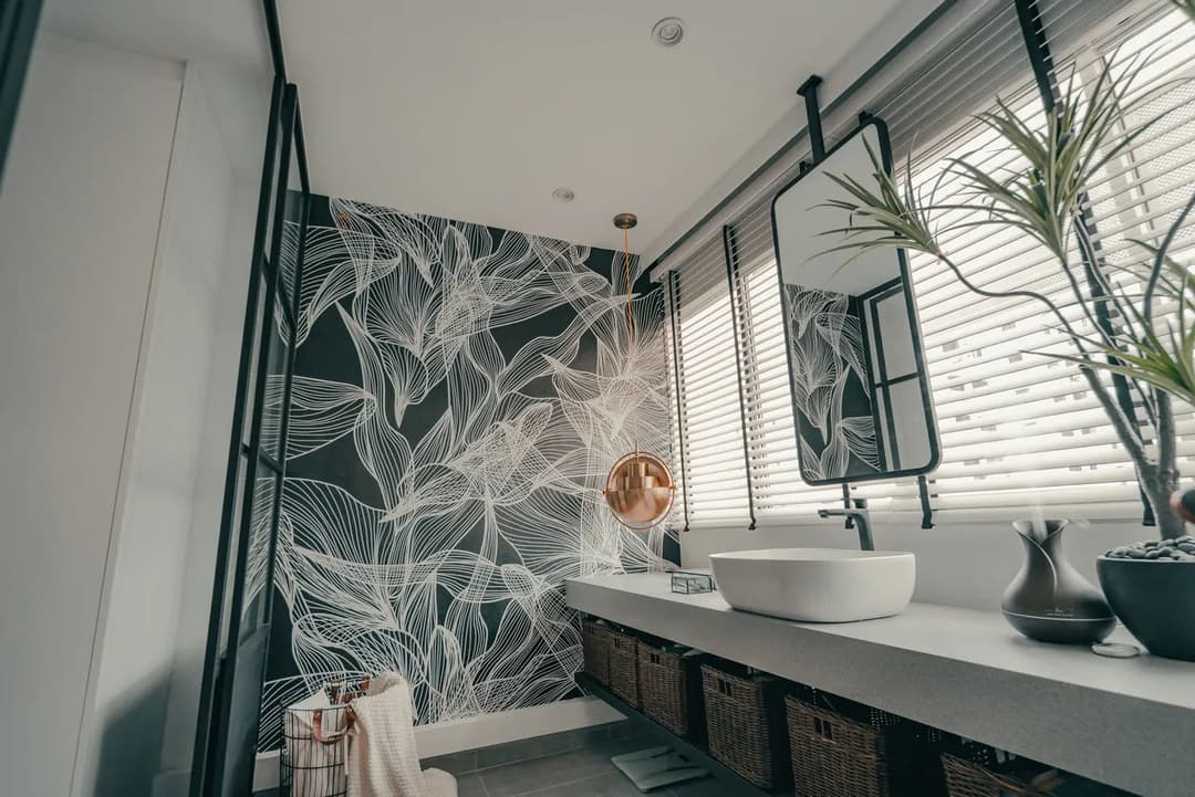Modern bathroom with floral wallpaper, sleek sink, and stylish decor. Natural light from windows.