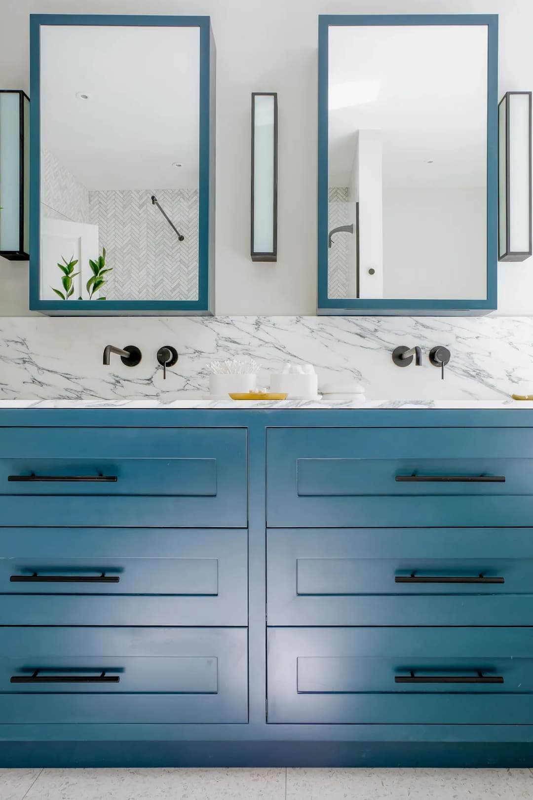 Modern bathroom with blue cabinetry, marble countertop, and dual mirrors. Stylish and functional design.