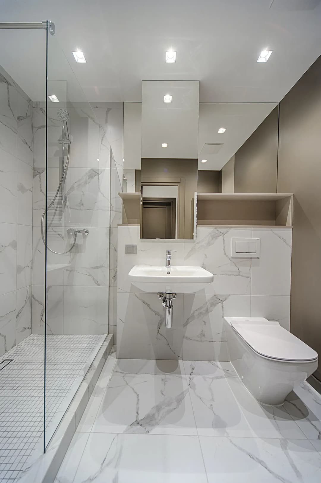 Modern bathroom with glass shower, marble tiles, sleek sink, and toilet. Minimalist design.