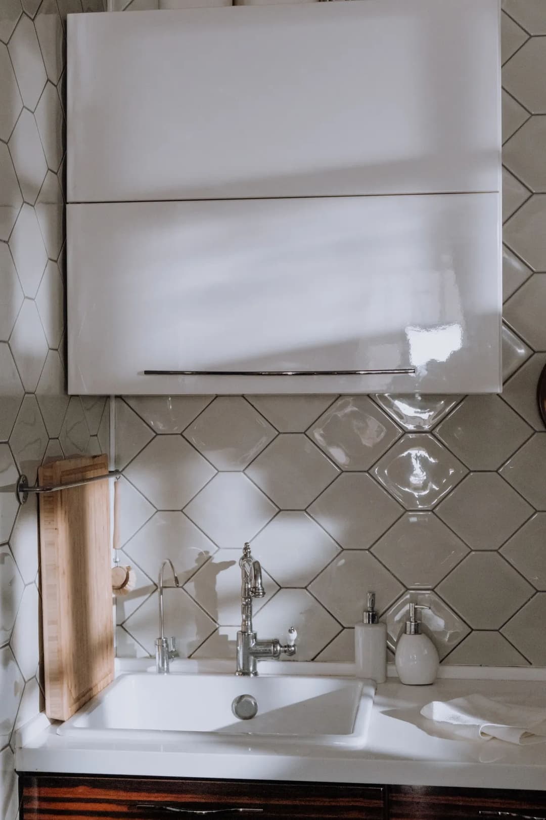 Modern bathroom with white cabinetry, hexagonal tiles, and elegant fixtures.