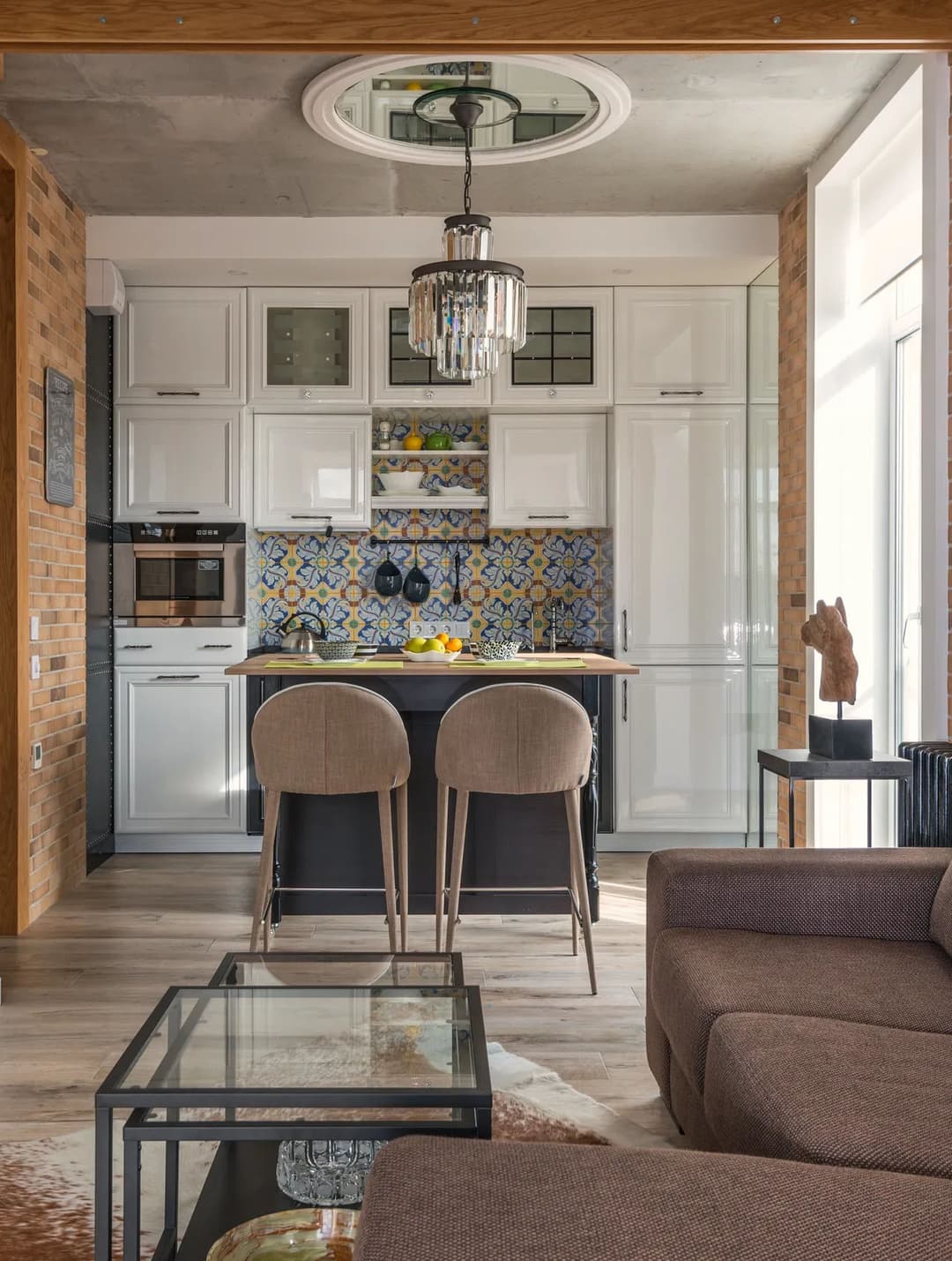 Modern kitchen with stylish decor, featuring bar stools, vibrant tiled backsplash, and chic lighting.