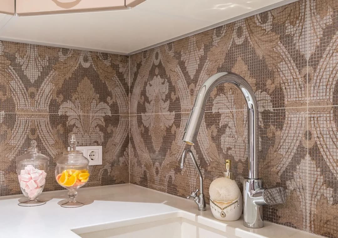 Modern kitchen backsplash with intricate mosaic design, stylish faucet, and decorative jars.