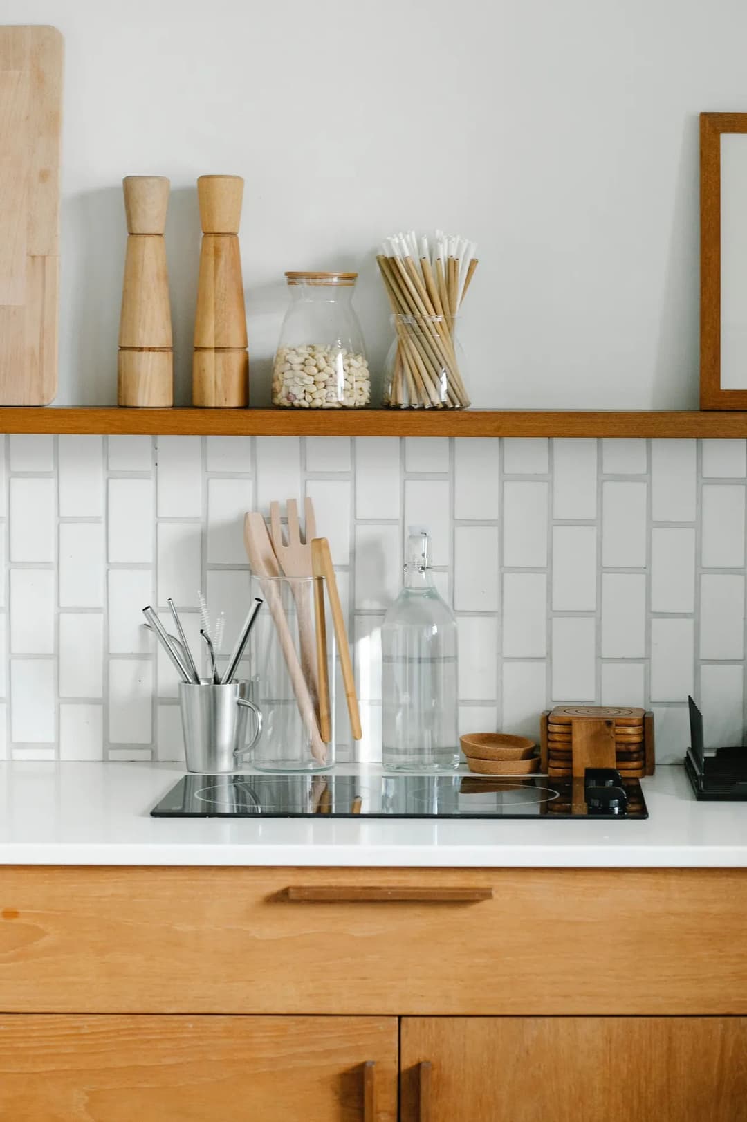 Modern kitchen countertop with wooden utensils, glass jars, and stylish backsplash.