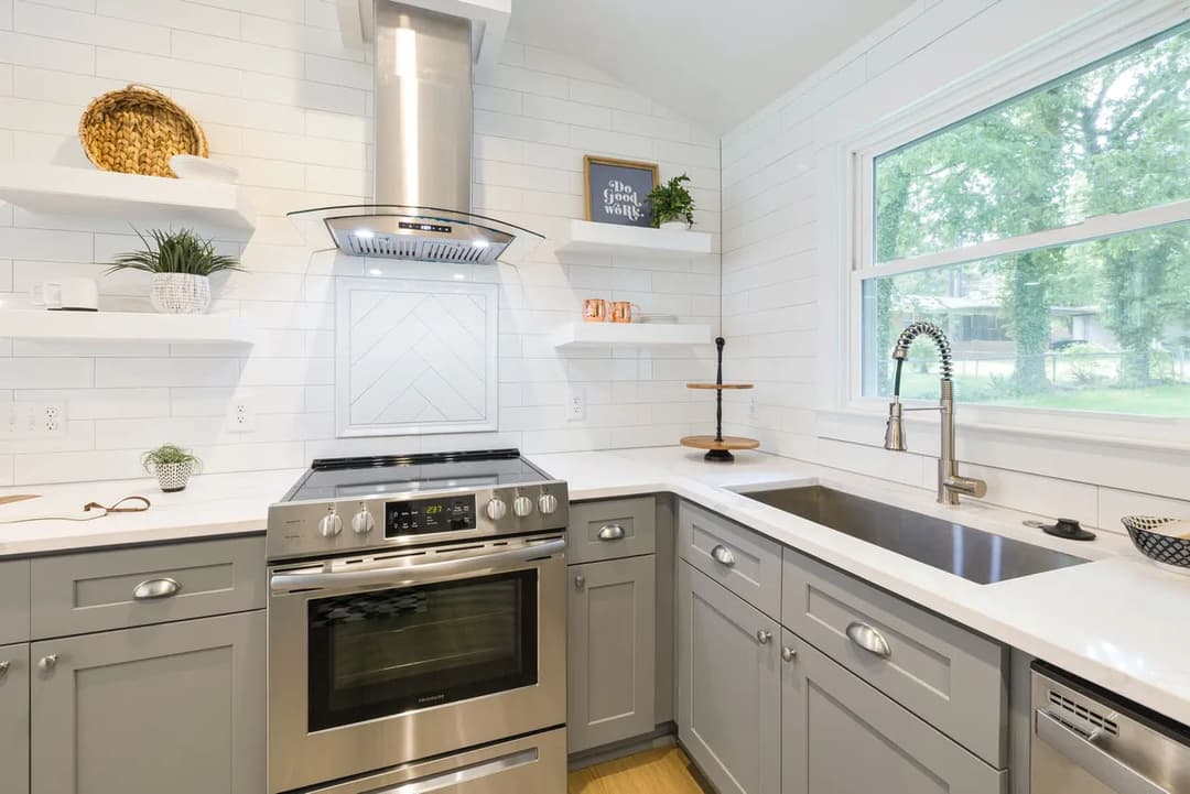 Modern kitchen with gray cabinets, stainless steel appliances, and white shiplap walls.