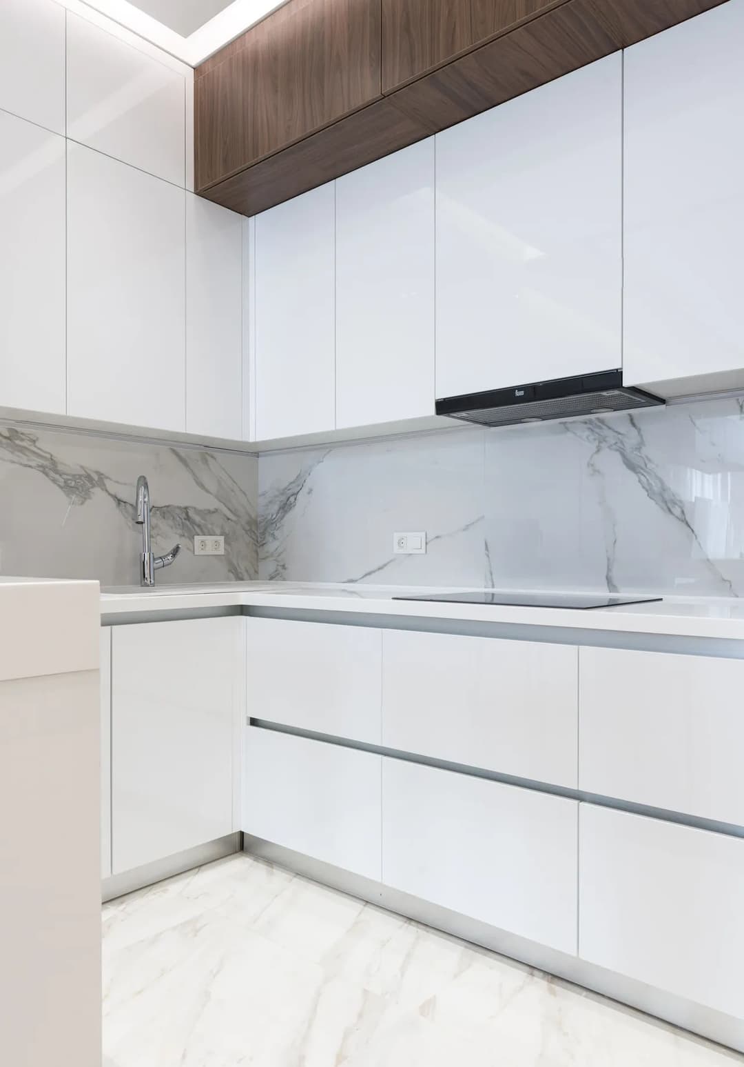 Modern minimalist kitchen with white cabinets, marble backsplash, and sleek design features.