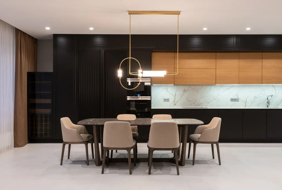 Modern kitchen with elegant dining table, beige chairs, and stylish lighting fixture.