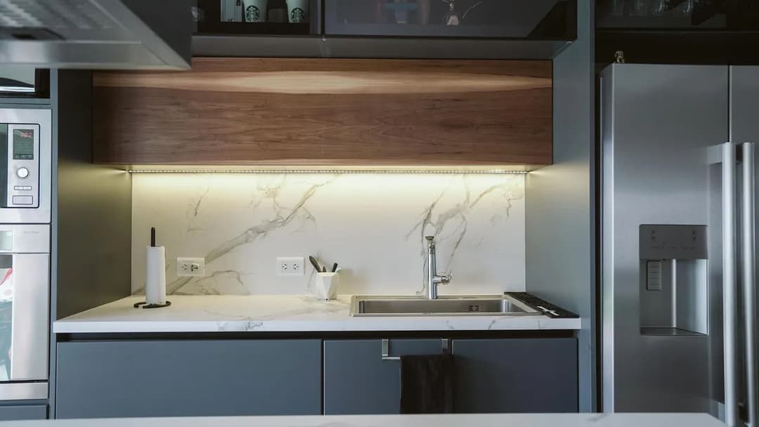 Modern kitchen with marble countertops, sleek cabinetry, and under-cabinet lighting.