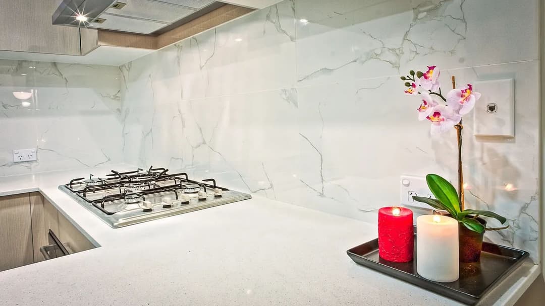 Modern kitchen with marble backsplash, gas stove, and decorative candles with an orchid.