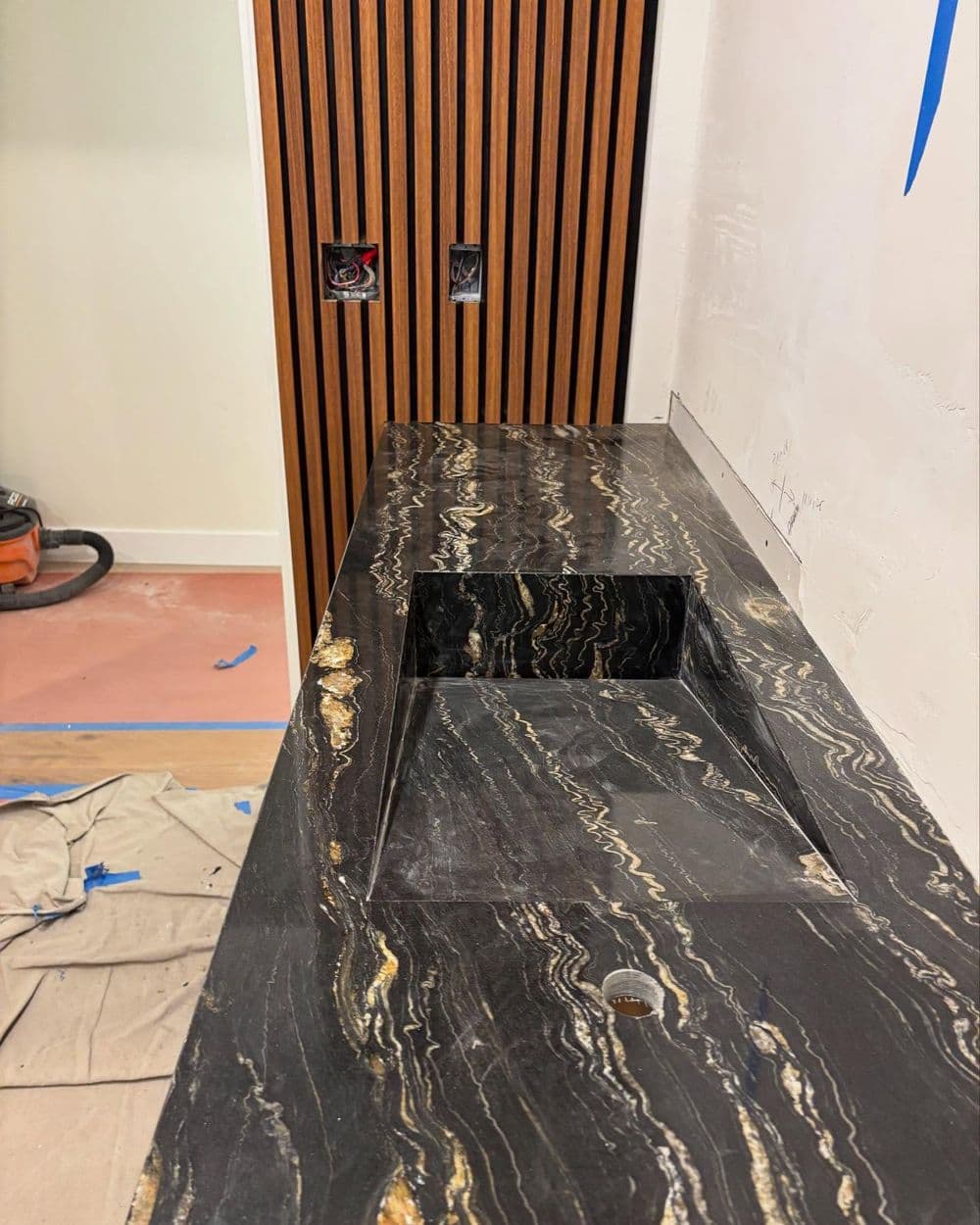 Marble countertop with a cutout sink area, wood paneling, and construction details visible.