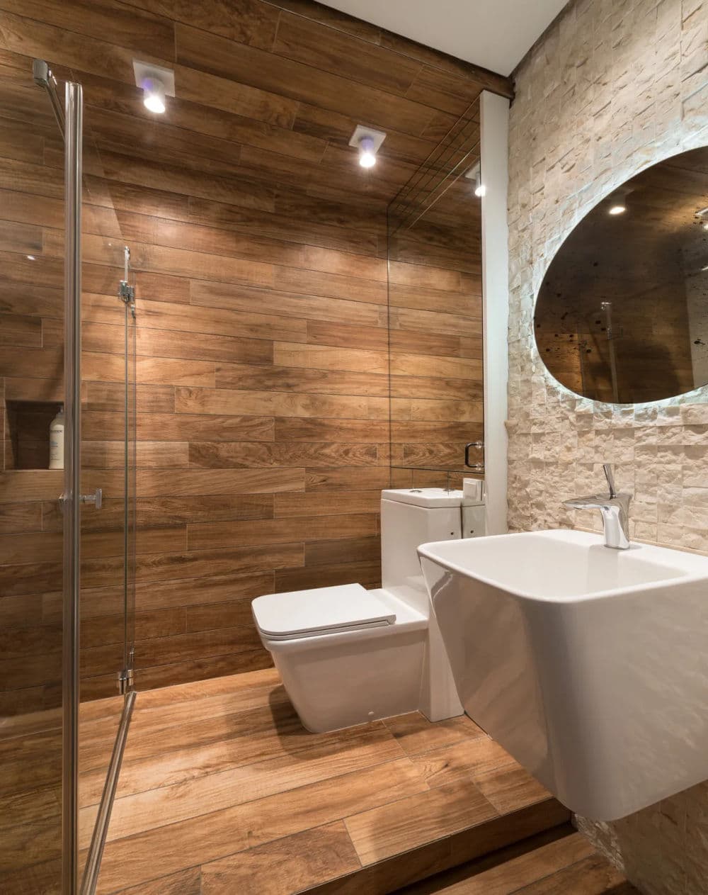 Modern bathroom with wooden accents, glass shower, and stylish white fixtures.