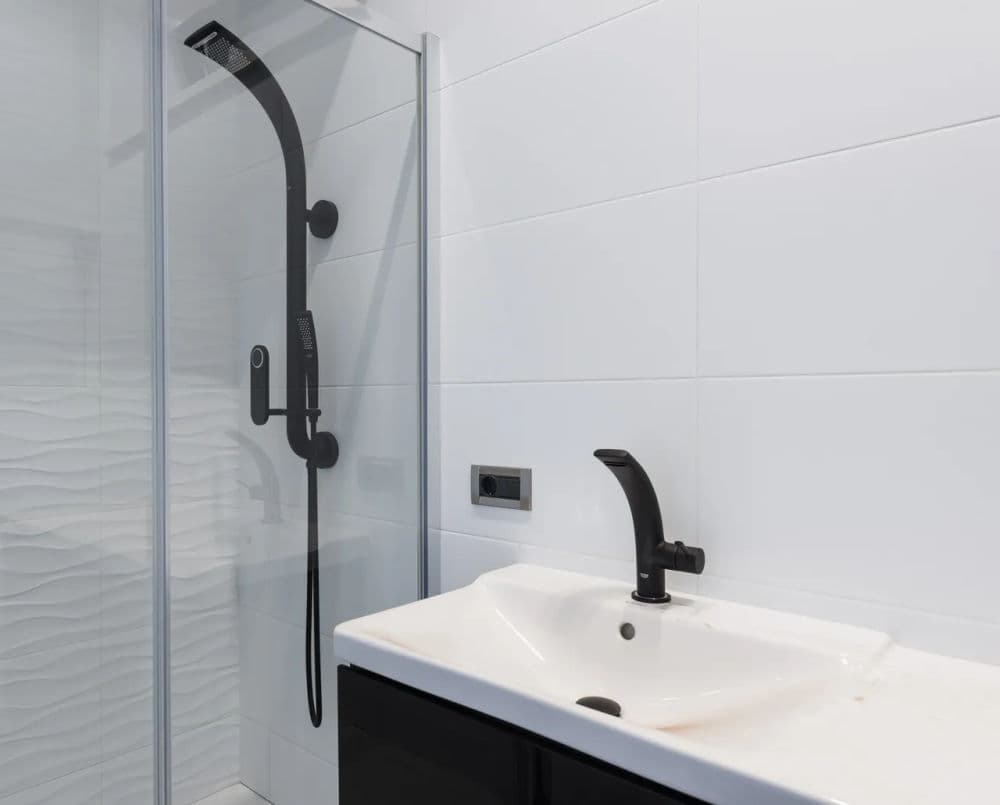 Modern bathroom featuring a sleek black shower fixture and minimalist sink design.