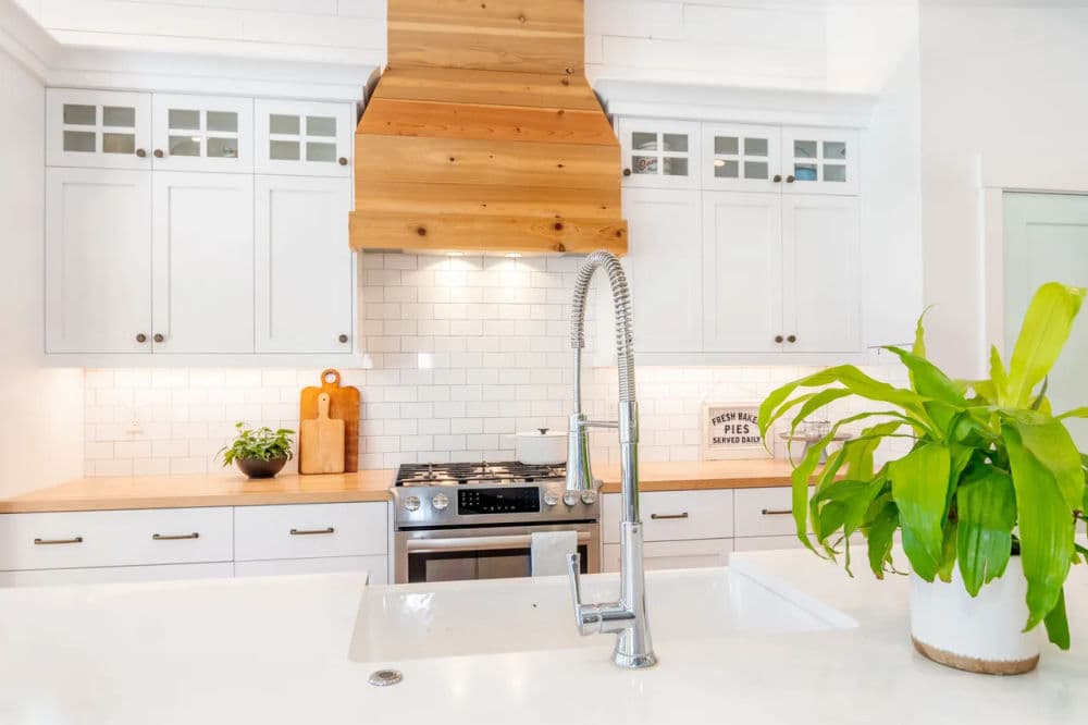 Modern kitchen with white cabinets, wooden accents, and stainless steel appliances.